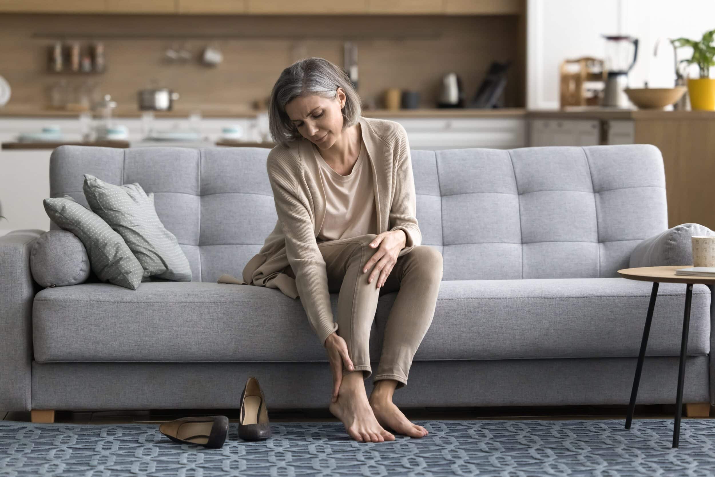 Older woman holding her ankle and looking at it due to venous ulcer in Tampa, FL
