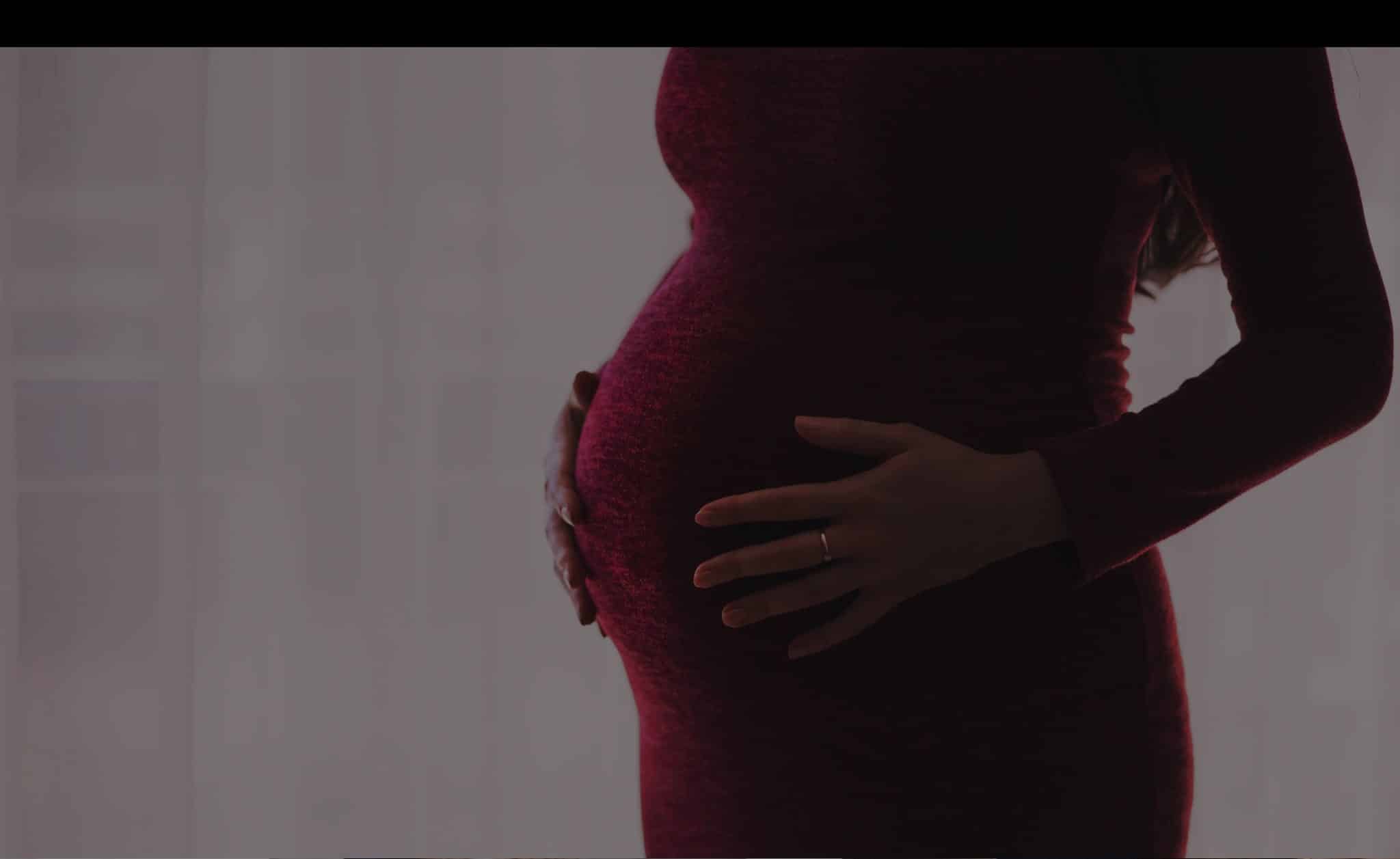 Woman's pregnant belly in red maternity dress