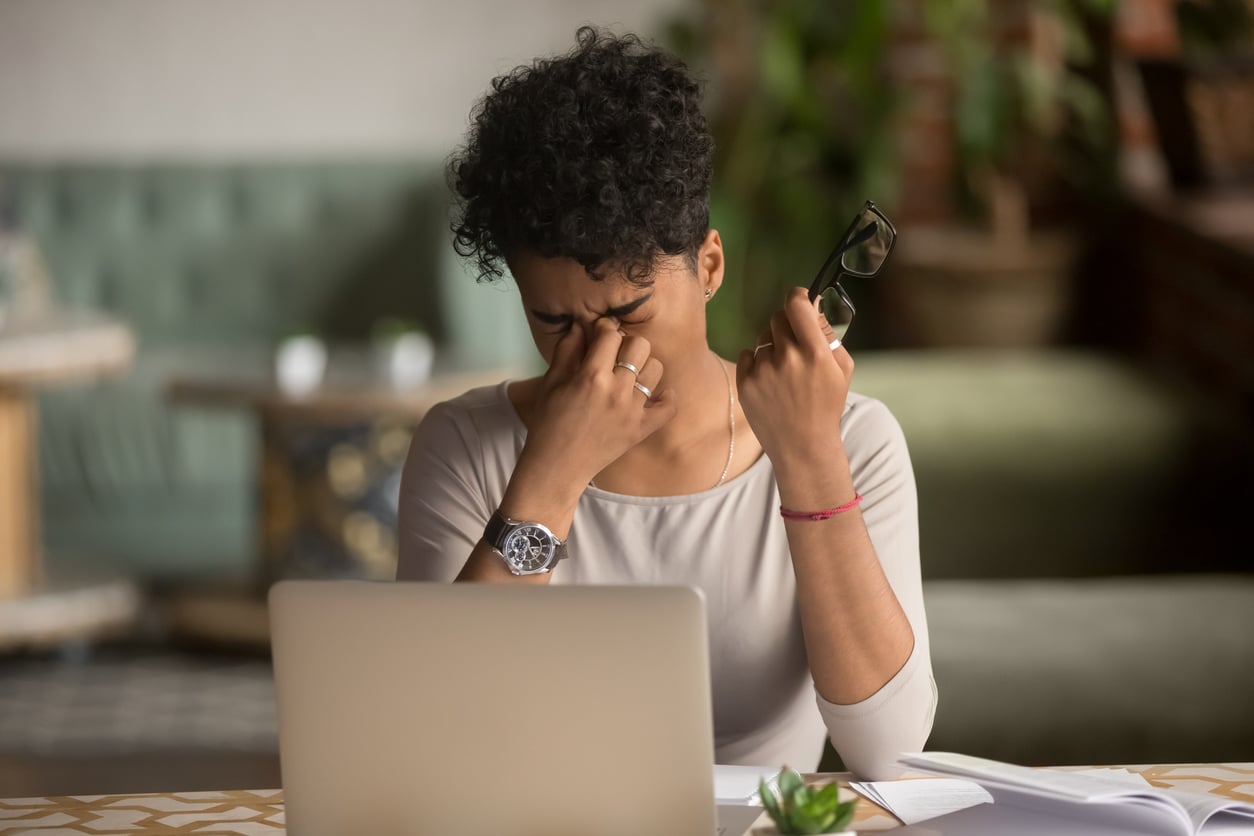 Photo of Overworked tired african female student worker holding glasses feel eye strain fatigue after computer work, mixed race woman suffer from pain in dry irritated eyes, bad blurry vision eyesight problem.